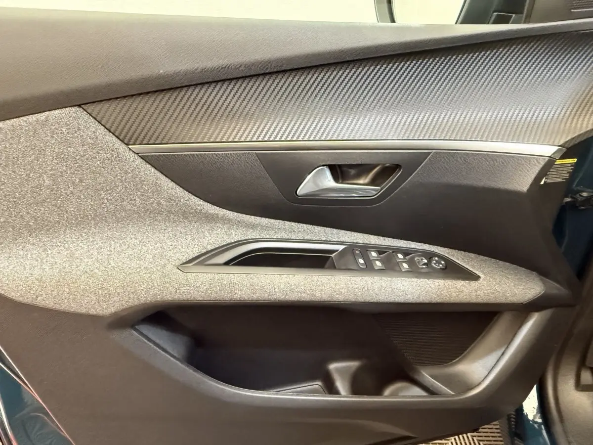 Vue rapprochée de la porte avant gauche du Peugeot 3008 bleu, avec commandes électriques et habillage texturé gris.