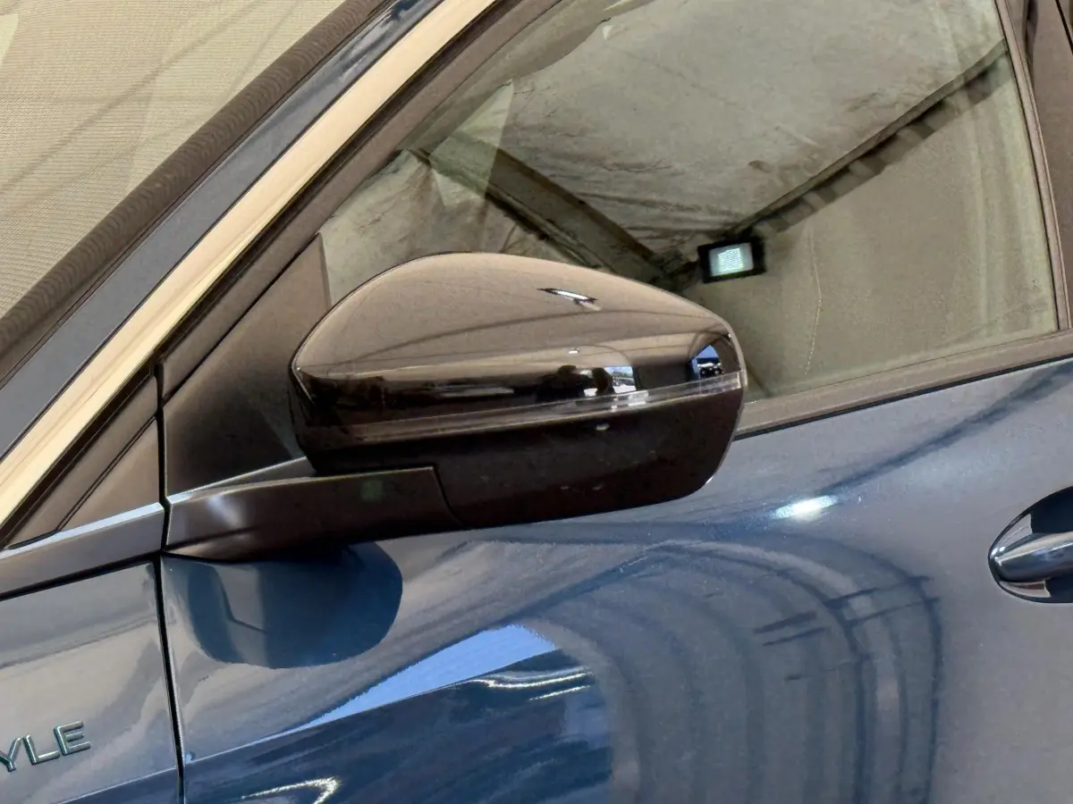 Rétroviseur droit noir brillant sur Peugeot 3008 bleu, vue rapprochée du côté conducteur avec poignée de porte visible.