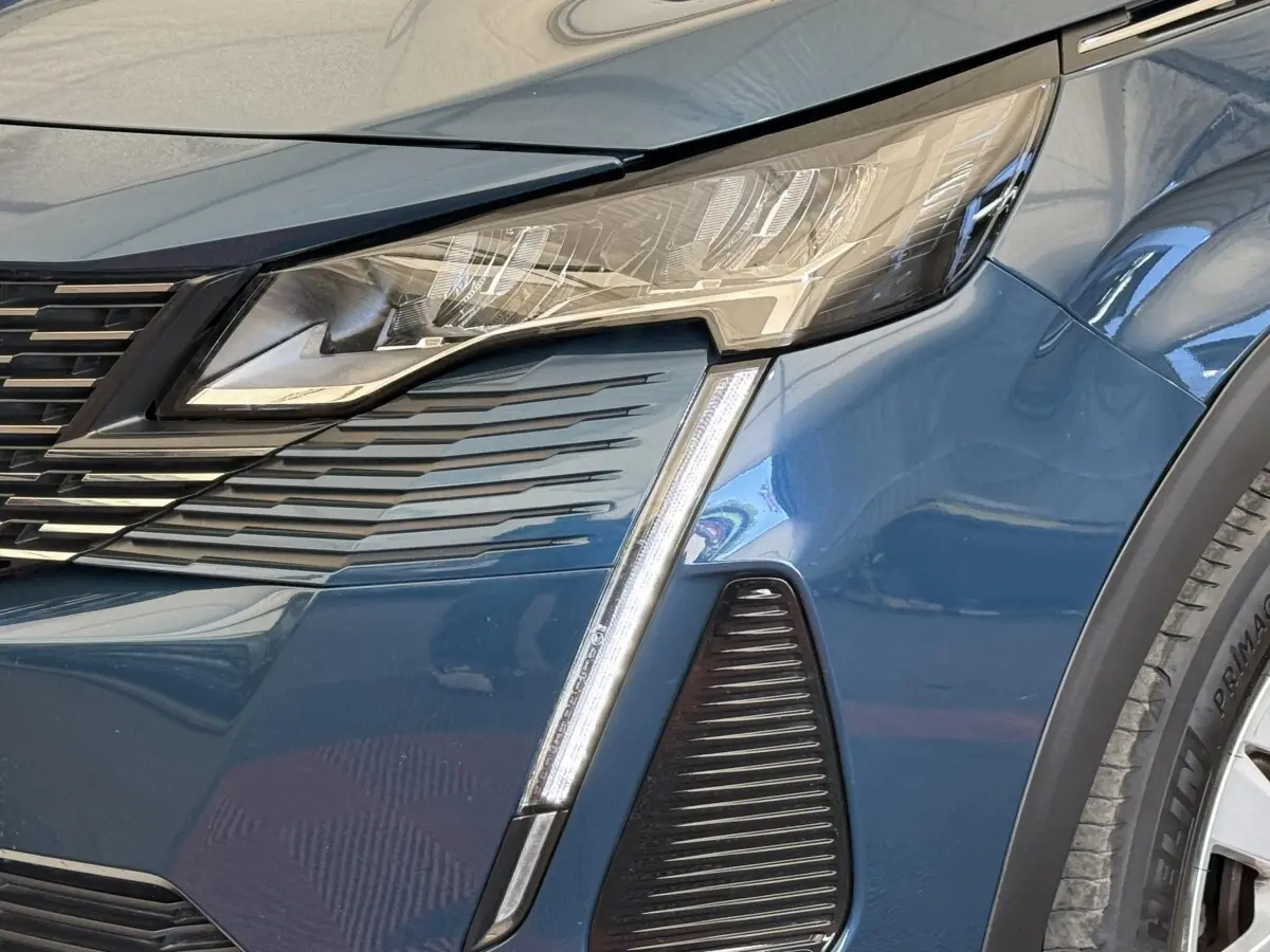 Gros plan sur le phare avant droit bleu du Peugeot 3008 2021 avec signature lumineuse en forme de griffes LED.