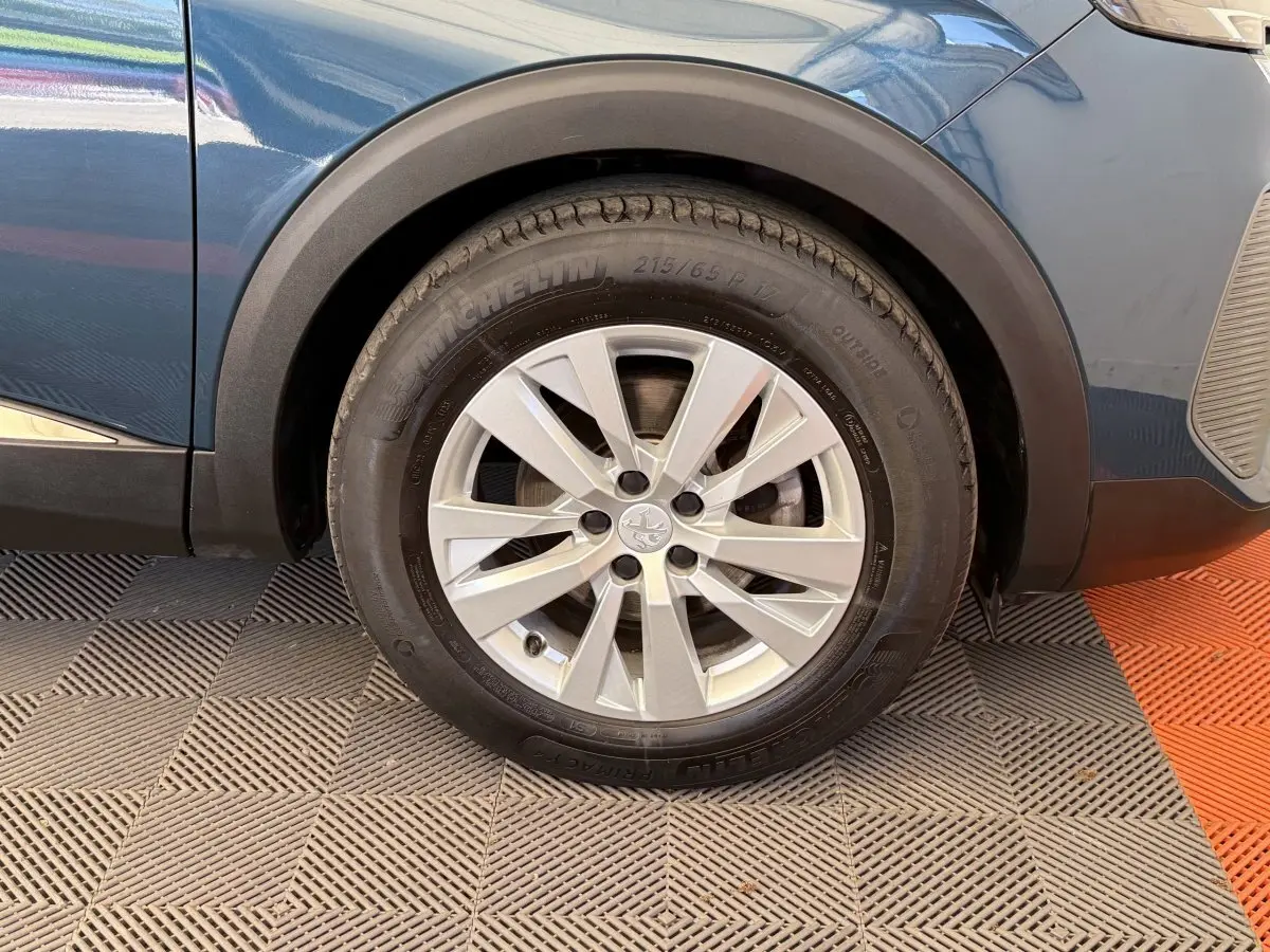 Gros plan sur la roue avant gauche du Peugeot 3008 bleu 2021 avec jante alliage et pneu Michelin.