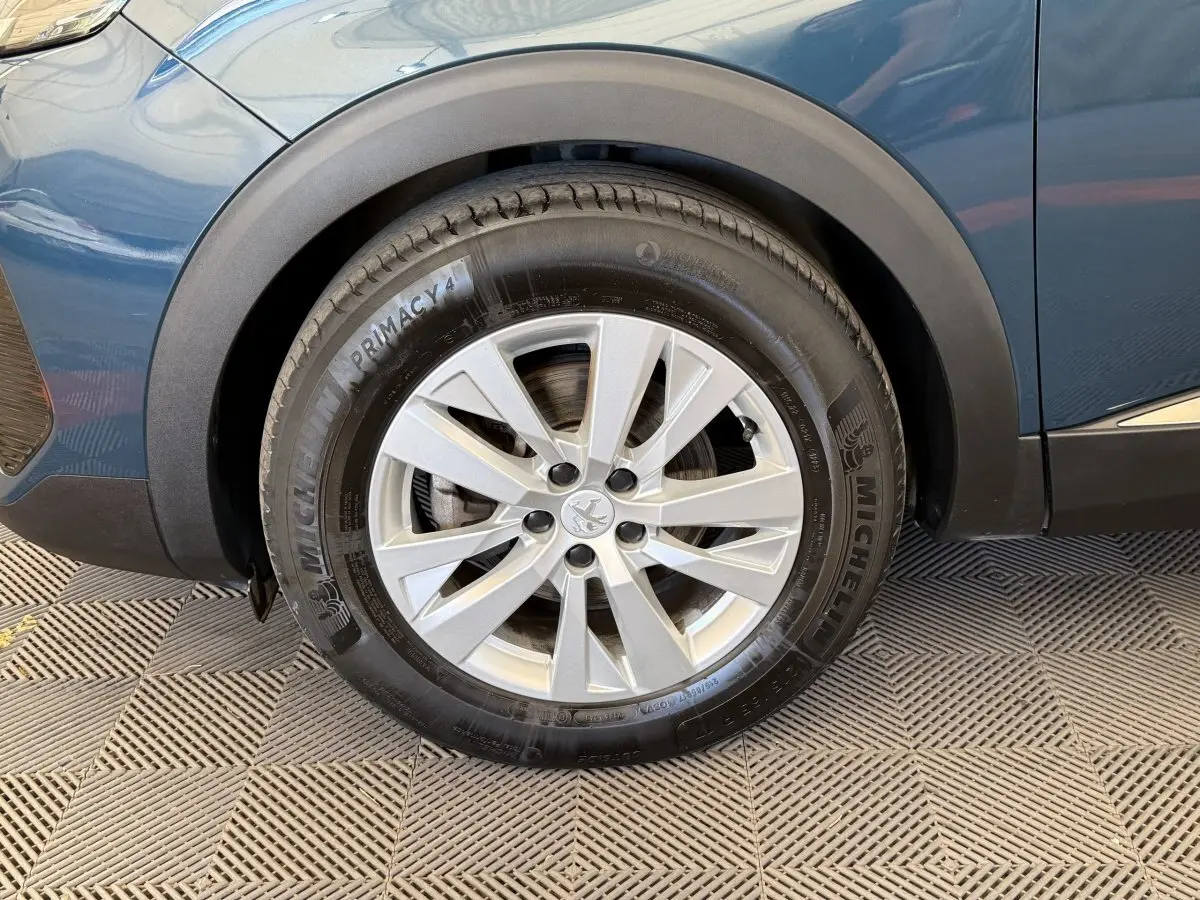 Gros plan sur la roue avant gauche d’un Peugeot 3008 bleu, avec jante alliage argentée et pneu Michelin.