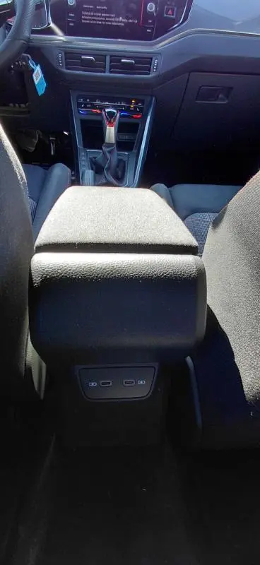 Vue intérieure centrée sur l'accoudoir central et la console avant d'une Volkswagen Polo GTI noire 2024 avec levier de vitesse automatique.