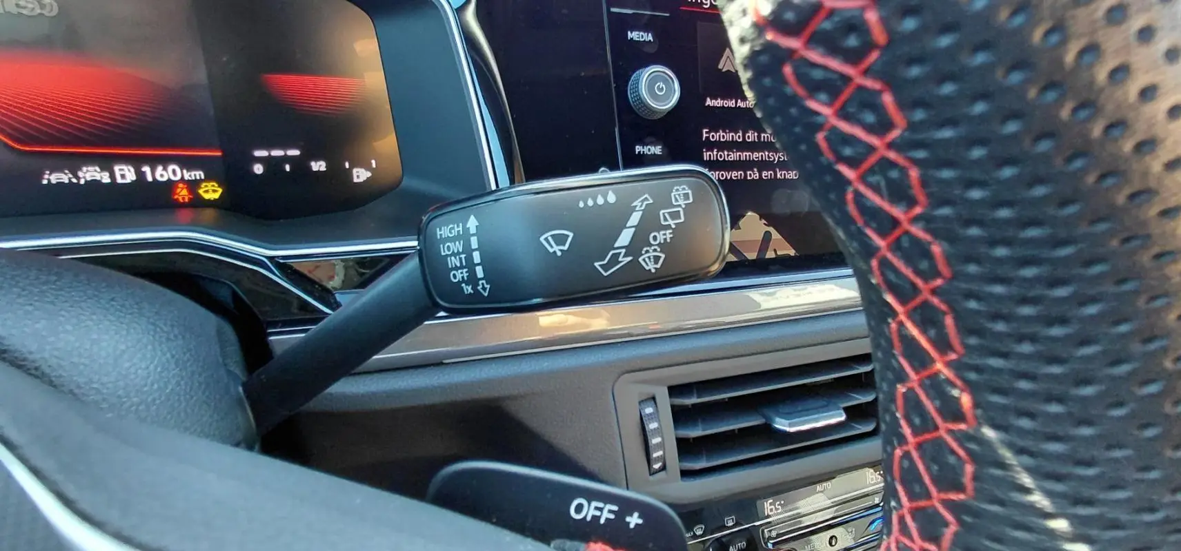 Gros plan sur le commodo d’essuie-glace et volant sport noir avec surpiqûres rouges dans l’habitacle d’une Volkswagen Polo GTI 2024.