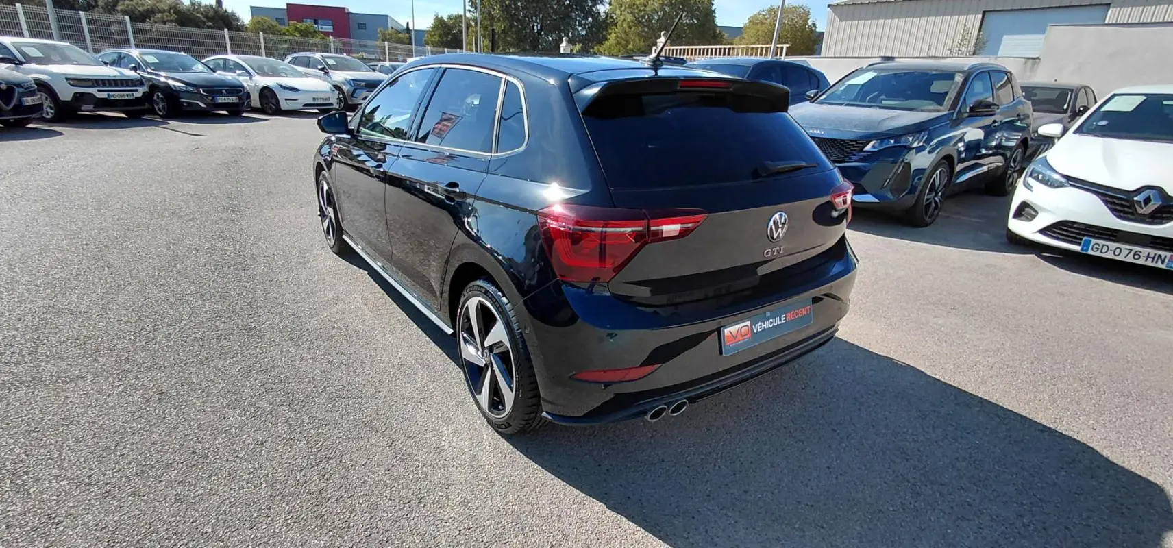 Vue 3/4 arrière droite d'une Volkswagen Polo GTI noire 2024 avec jantes alliage 17 pouces et double sortie d'échappement.