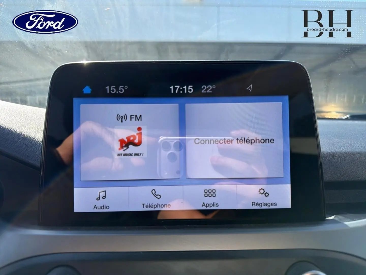 Écran tactile central de la Ford Focus 1.0 Flexifuel 2022 affichant la radio NRJ et les options de connexion téléphone.