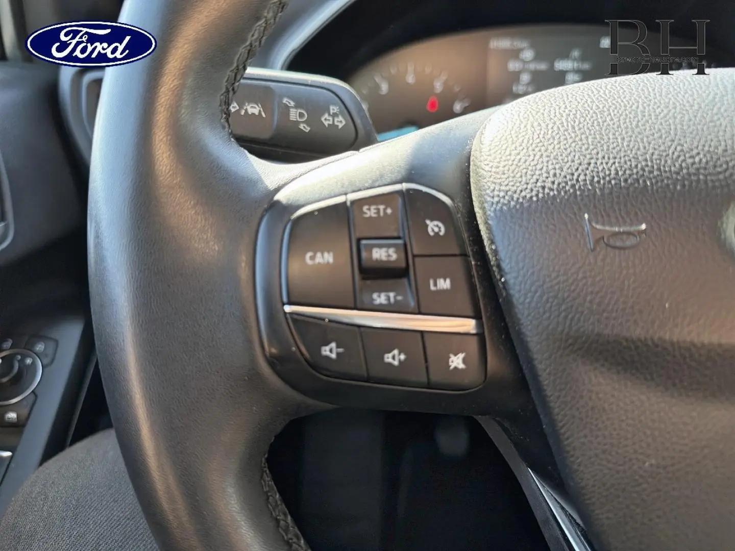 Gros plan sur le volant cuir multifonction noir de la Ford Focus 2022, avec commandes de régulateur et audio visibles.