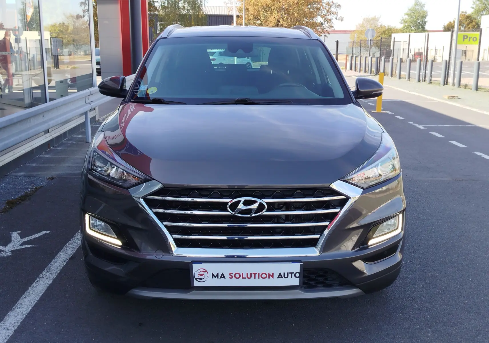 Vue avant d'un Hyundai Tucson gris Micron 2019 avec calandre chromée et feux LED allumés.