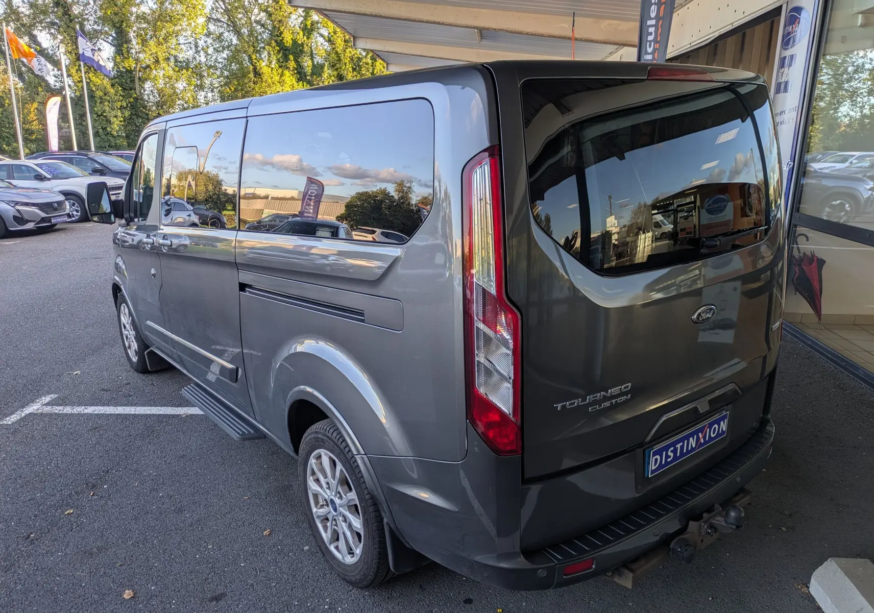 Vue 3/4 arrière droite d’un Ford Tourneo Custom gris 2019 avec vitres teintées et porte latérale coulissante visible.