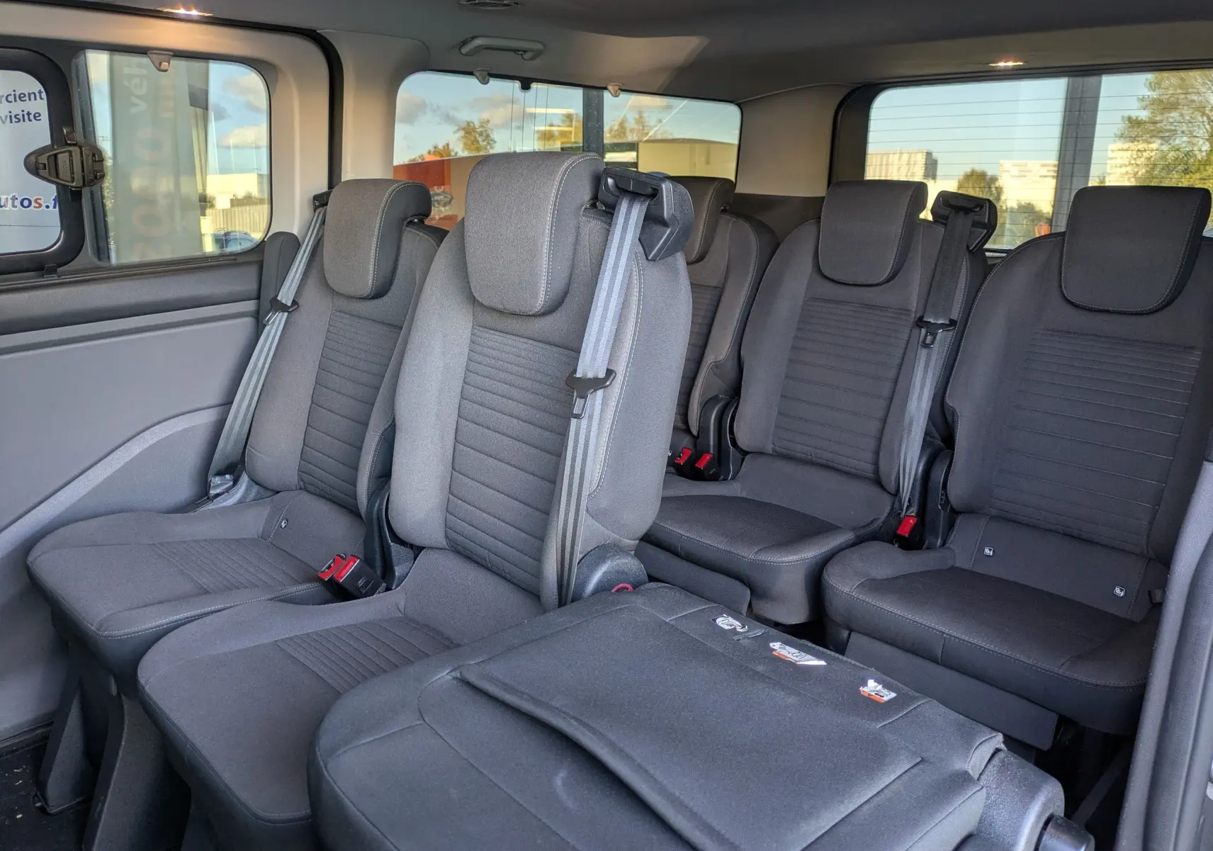 Vue intérieure côté gauche du Ford Tourneo Custom 2019, montrant les sièges gris en tissu pour 8 places.