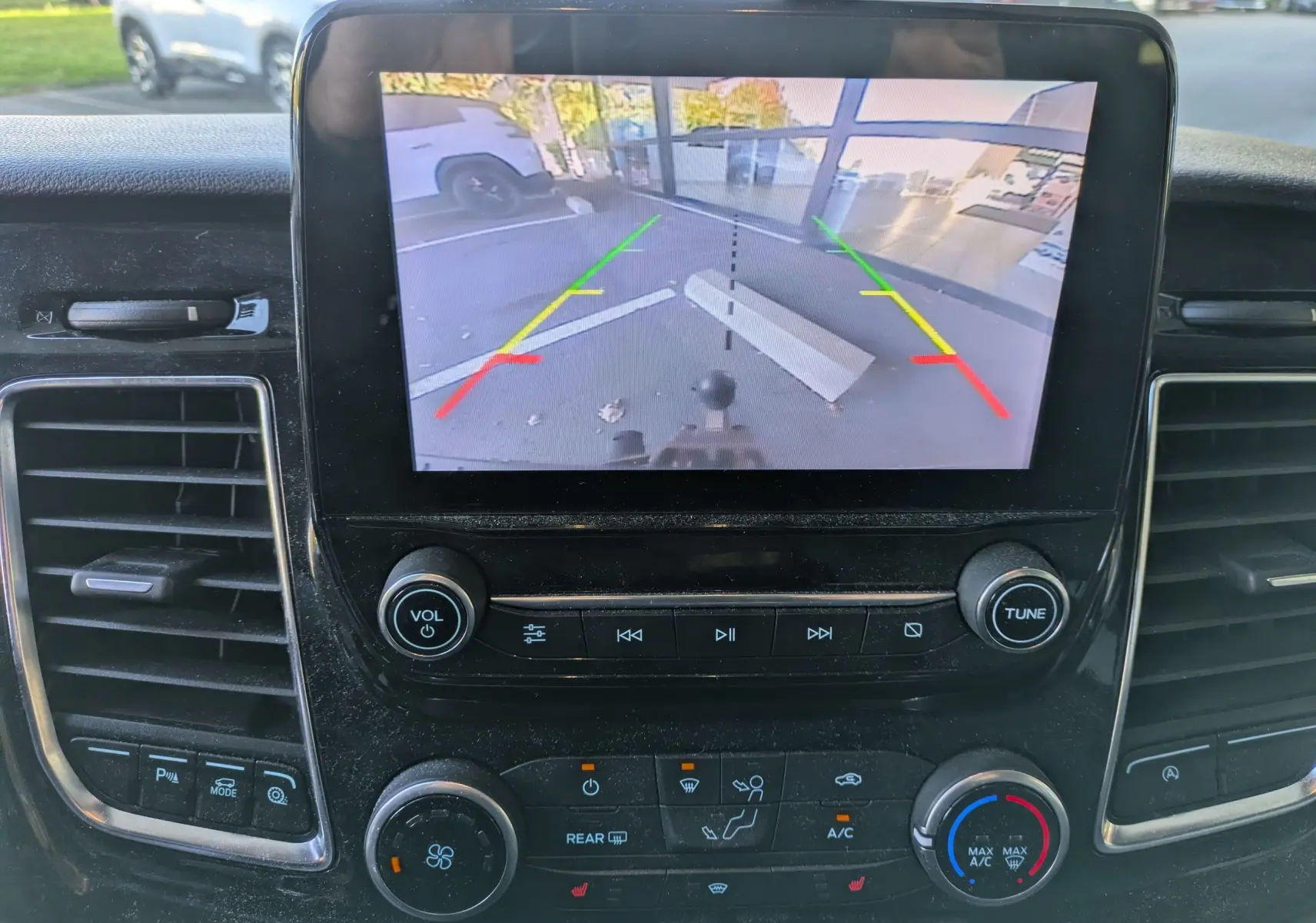 Vue rapprochée de l’écran central du Ford Tourneo Custom gris 2019 montrant la caméra de recul et les commandes de climatisation.