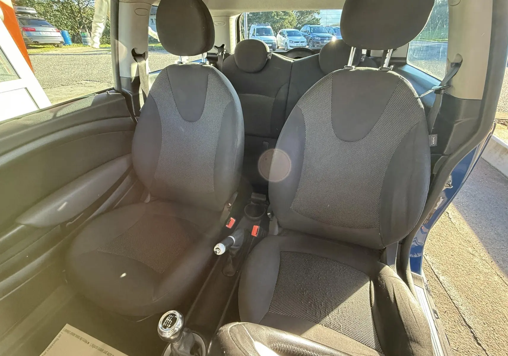 Vue intérieure de la MINI Cooper 2007 bleu, montrant les sièges avant en tissu gris et la boîte manuelle.