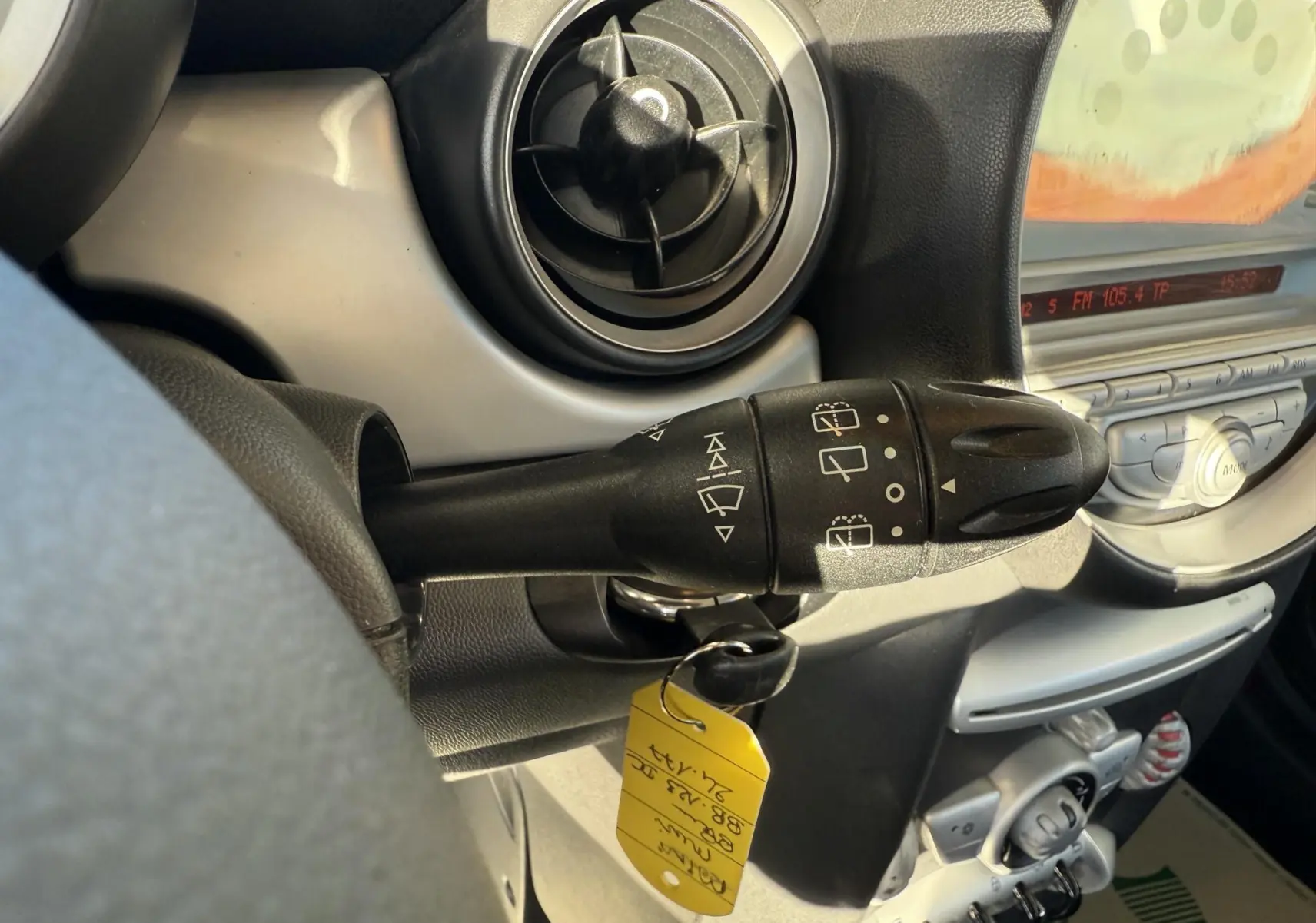 Gros plan sur la commande d'essuie-glace à gauche du volant dans l'habitacle gris d'une MINI Cooper bleu 2007.