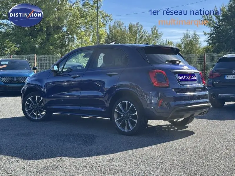 Fiat 500X bleu foncé en 3/4 arrière droit, avec jantes alliage et feux arrière LED visibles.