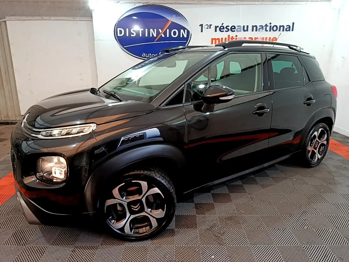 Citroën C3 Aircross noir vue 3/4 avant droit, avec jantes distinctives et barres de toit noires visibles.