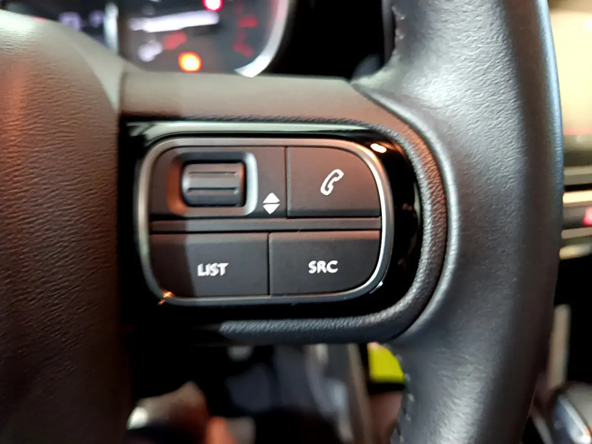 Gros plan sur les commandes gauche du volant cuir noir du Citroën C3 Aircross 2019, boutons LIST et SRC visibles.