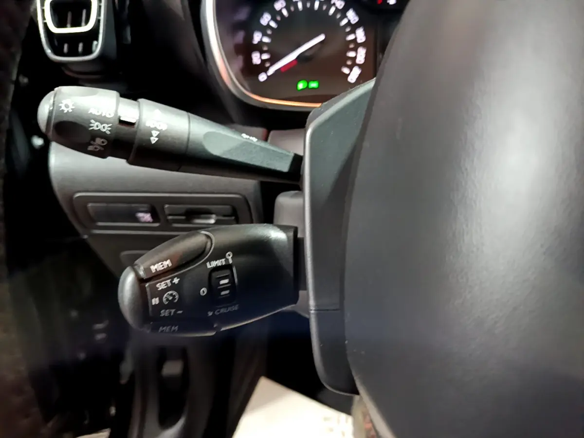 Gros plan côté gauche du volant cuir du Citroën C3 Aircross noir, avec commandes de régulateur et feux visibles.