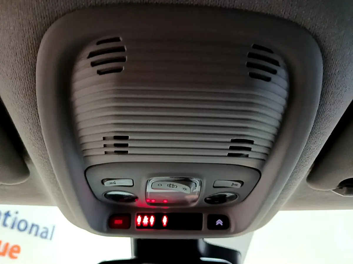 Plafonnier intérieur gris avec commandes d'éclairage et alertes rouges, vue en contre-plongée dans un Citroën C3 Aircross noir.