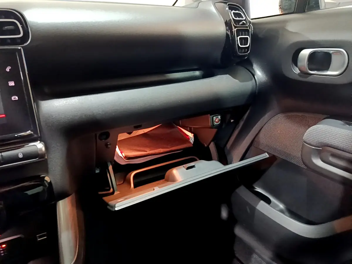 Intérieur du Citroën C3 Aircross noir 2019, vue côté passager sur la boîte à gants ouverte et tableau de bord.