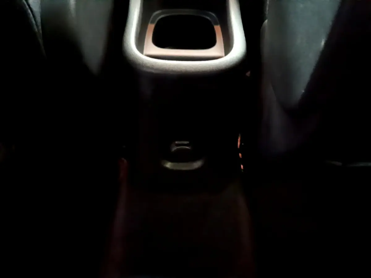 Vue rapprochée de la console centrale arrière noire du Citroën C3 Aircross, avec prise 12V visible entre les sièges arrière.