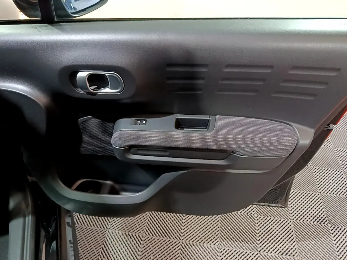 Gros plan sur la porte intérieure côté gauche noire du Citroën C3 Aircross avec poignée et accoudoir tissu.