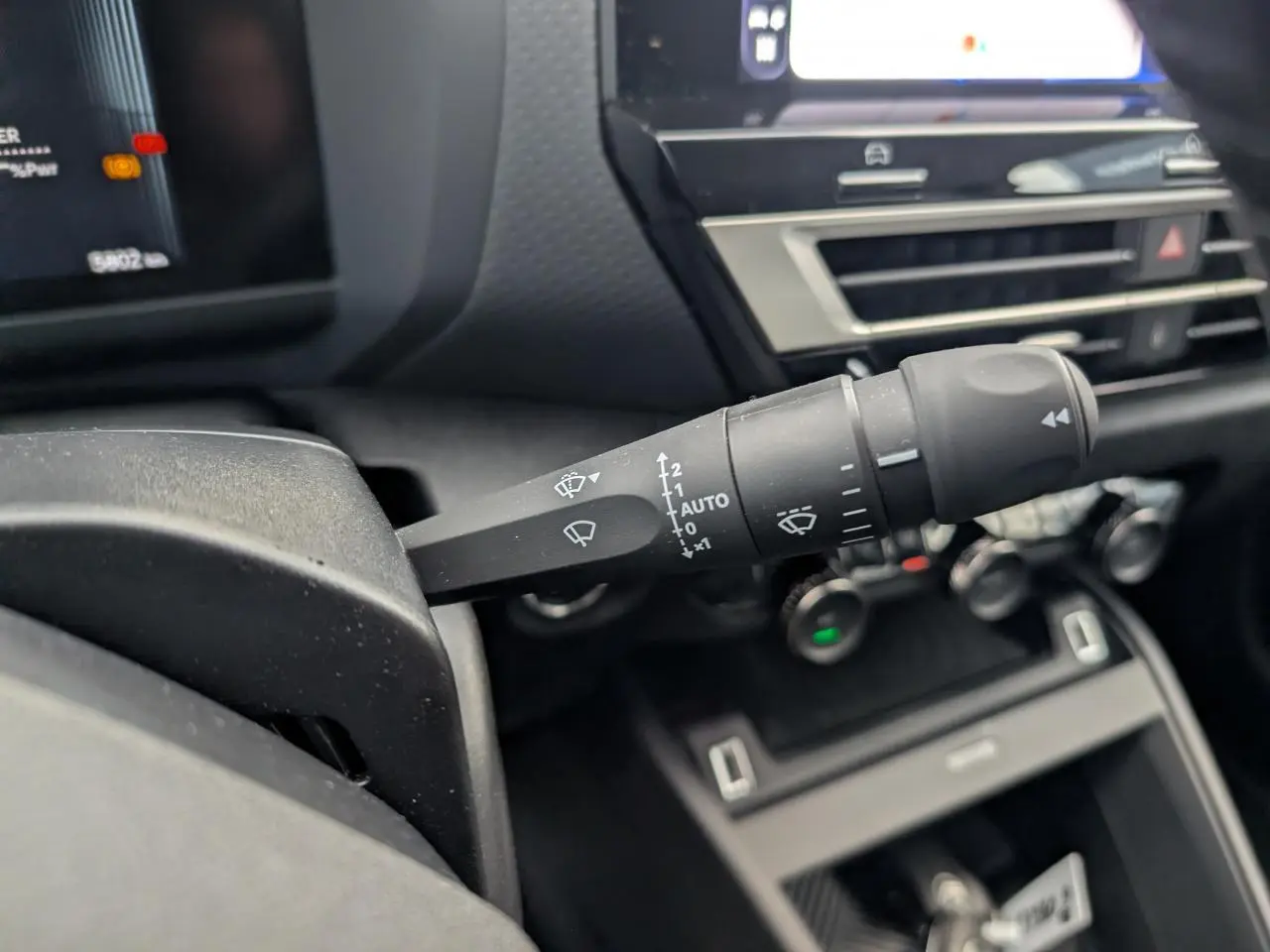 Gros plan sur la commande d'essuie-glace à gauche du volant dans l'habitacle de la Citroën C4 blanche 2025.