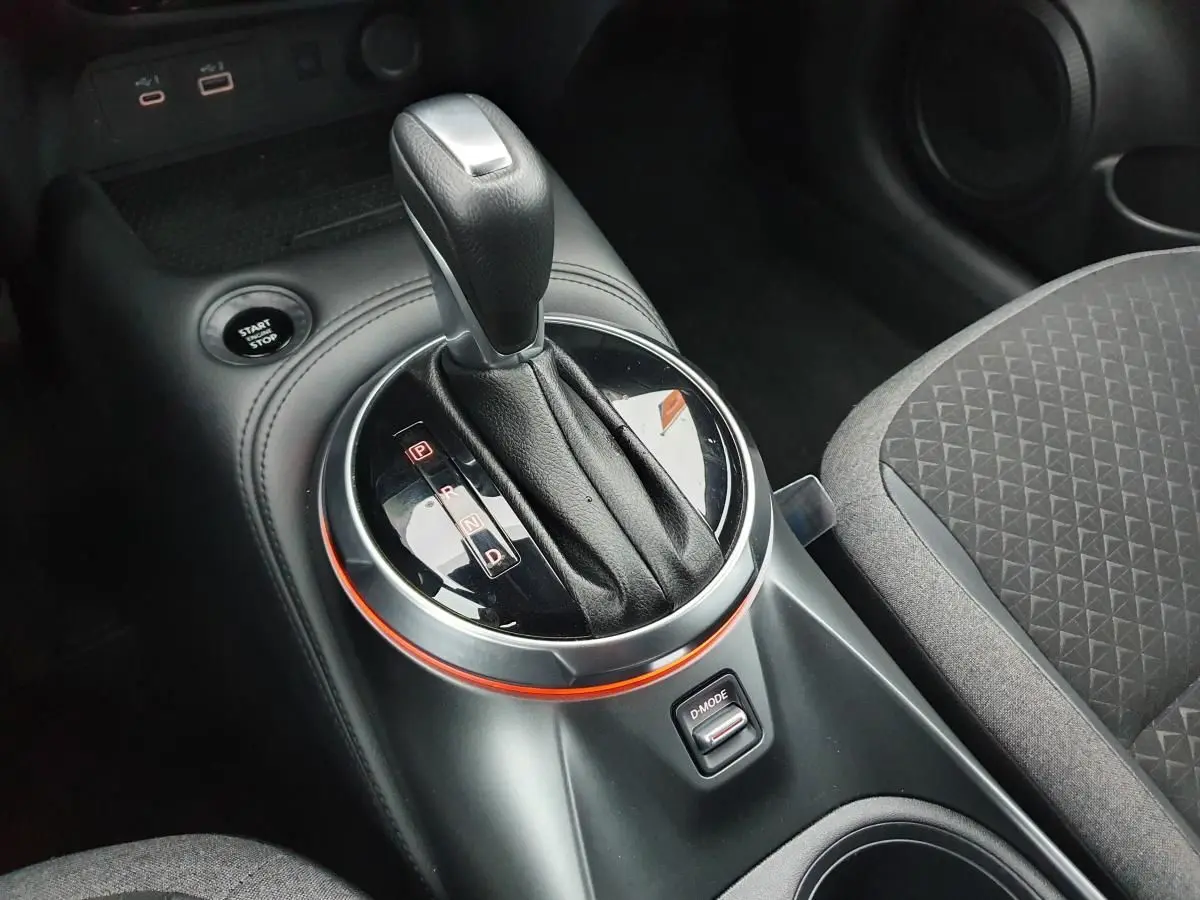 Gros plan sur la commande de boîte automatique noire et bouton Start/Stop du Nissan Juke 2025, intérieur tissu gris.