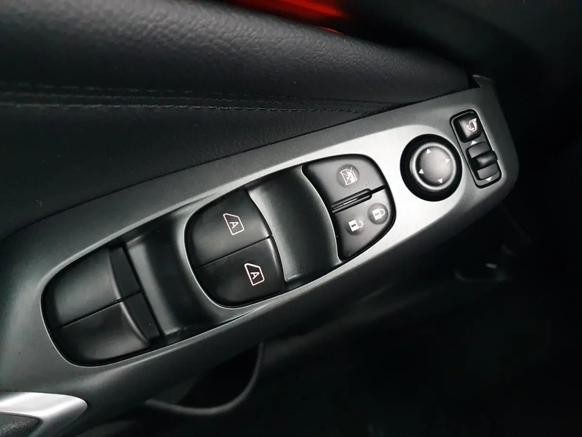 Gros plan sur les commandes de lève-vitres et rétroviseurs côté gauche intérieur du Nissan Juke noir 2025.