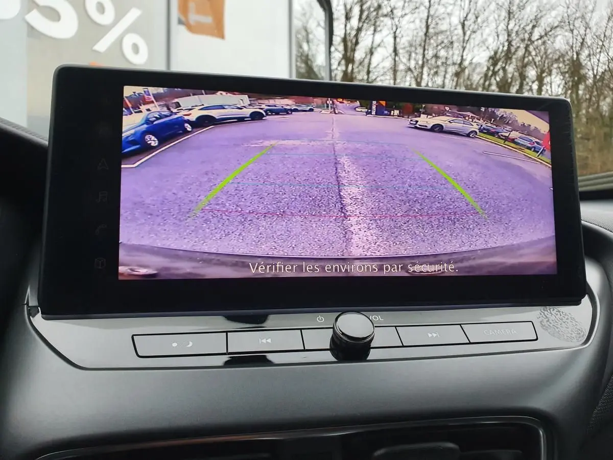 Écran tactile intérieur montrant la caméra de recul du Nissan Juke noir, avec lignes d'aide au stationnement visibles.
