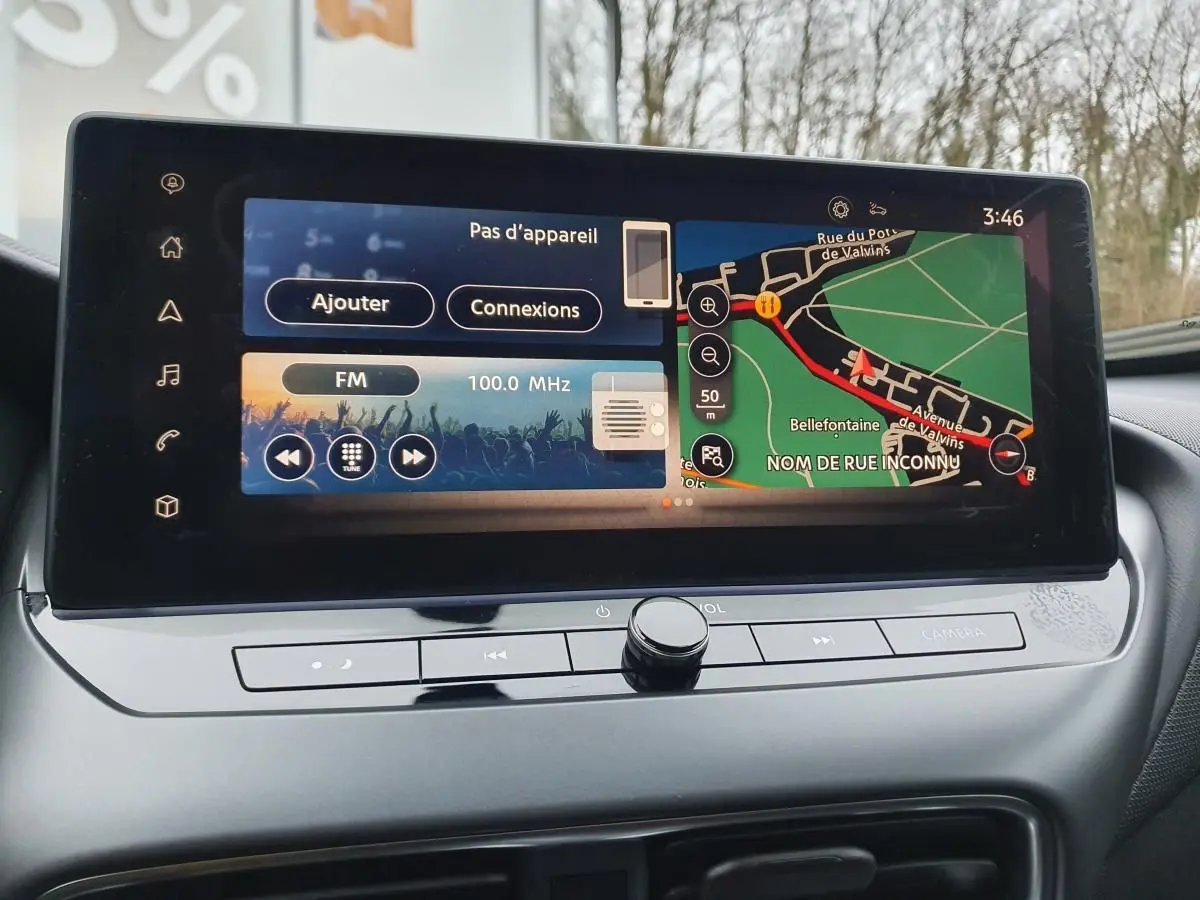 Écran tactile 12,3'' du Nissan Juke 2025 affichant navigation et radio, vue rapprochée du tableau de bord intérieur.