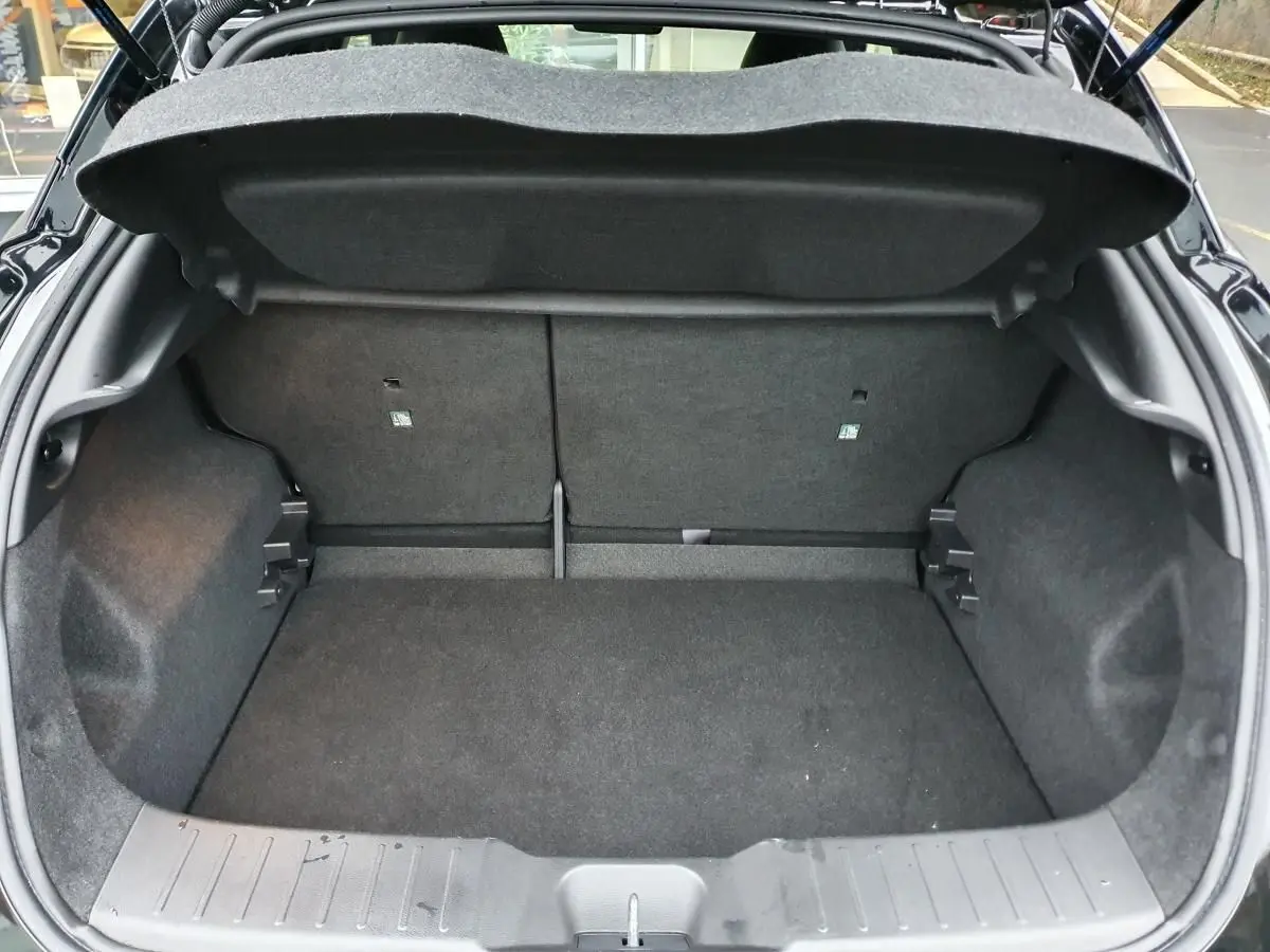 Coffre ouvert vu de l'arrière d'un Nissan Juke noir 2025, montrant l'espace de chargement vide et la banquette rabattable.