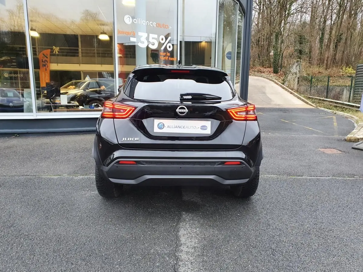 Vue arrière d'un Nissan Juke noir 2025 avec feux LED allumés, garé devant une vitrine de concession.
