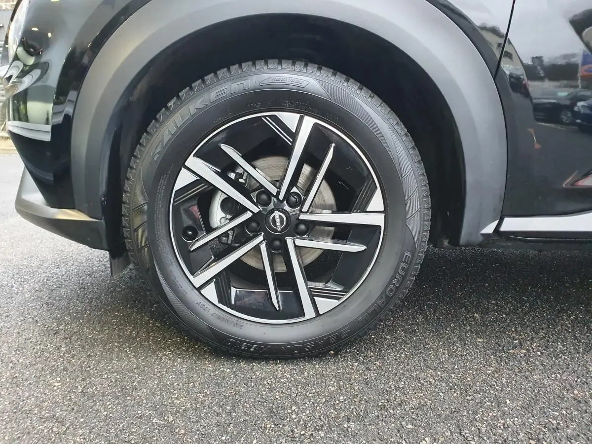 Gros plan sur la roue avant gauche noire du Nissan Juke 2025 avec jante alliage 17 pouces au design moderne.