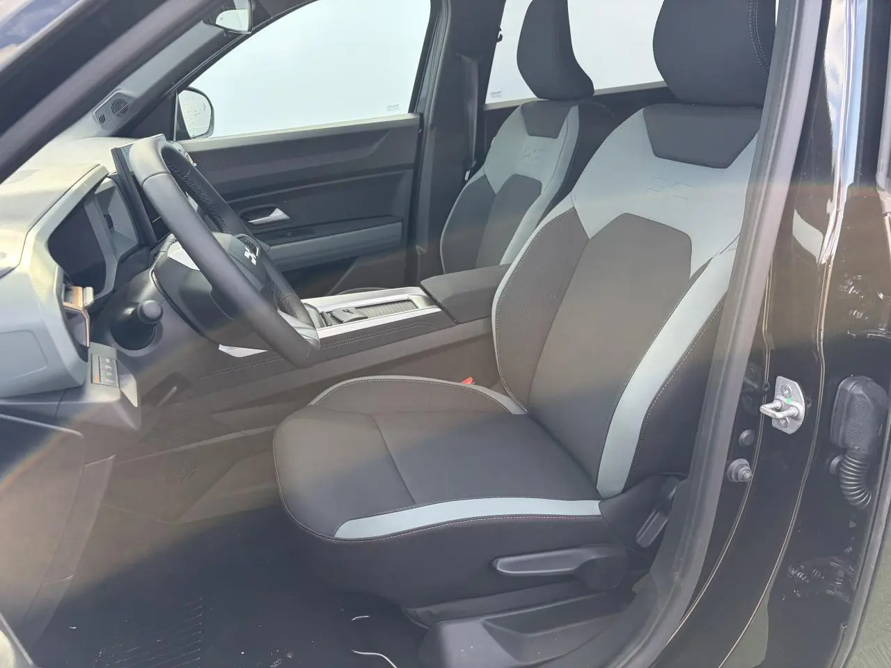 Vue intérieure côté conducteur du Dacia Bigster noir, mettant en valeur les sièges avant bicolores et le volant multifonction.