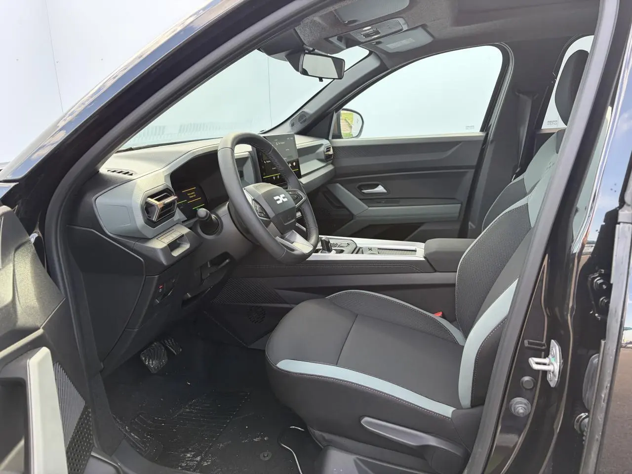 Vue intérieure côté conducteur du Dacia Bigster noir avec sellerie bicolore et tableau de bord moderne.