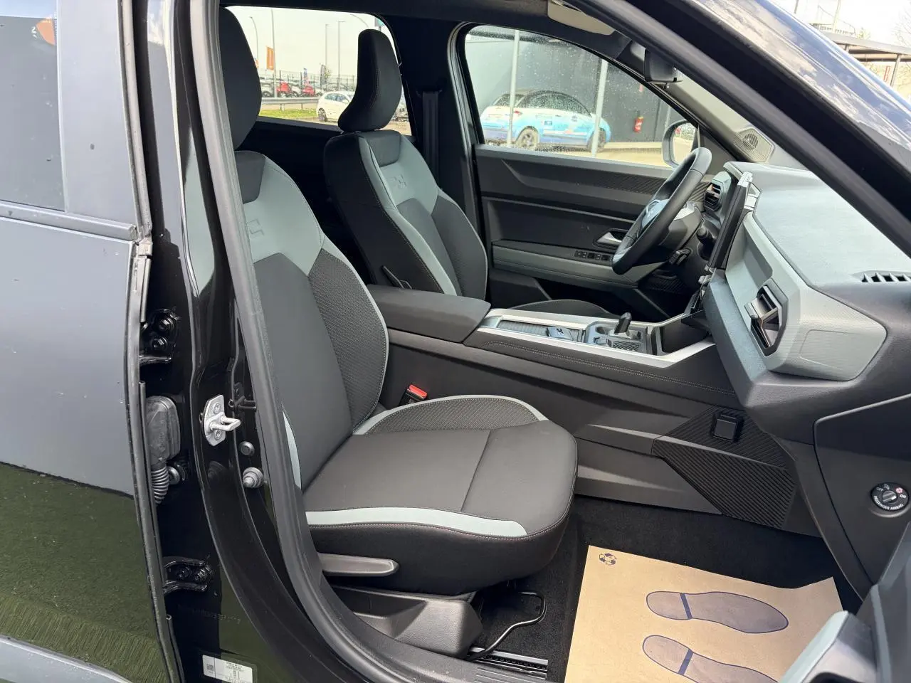 Vue intérieure côté conducteur du Dacia Bigster noir, mettant en valeur les sièges avant et la console centrale moderne.