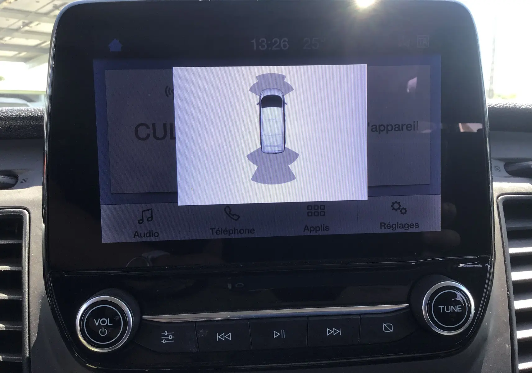 Écran central du Ford Transit Custom Kombi montrant une vue de dessus du véhicule blanc avec capteurs de proximité activés.
