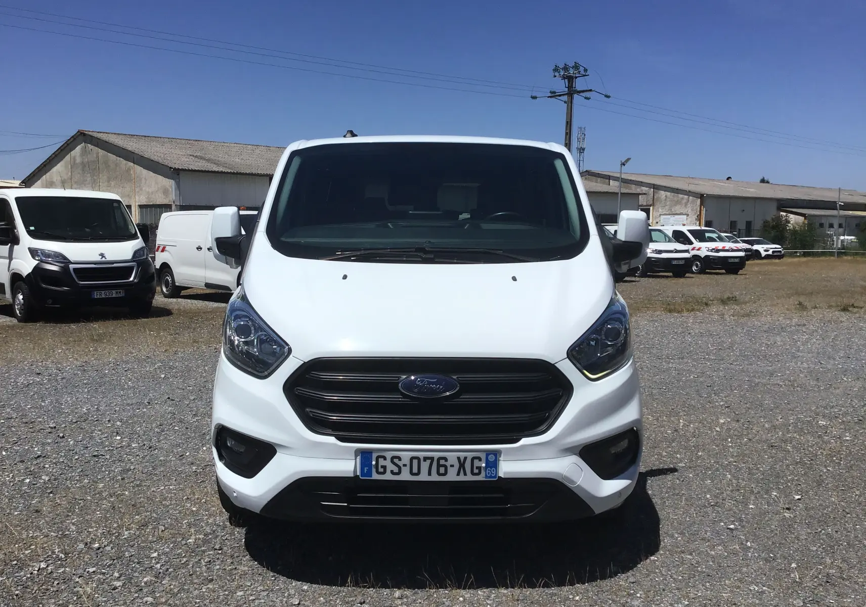 Vue de face d’un Ford Transit Custom Kombi blanc 2023, avec calandre noire et plaque d’immatriculation française visible.
