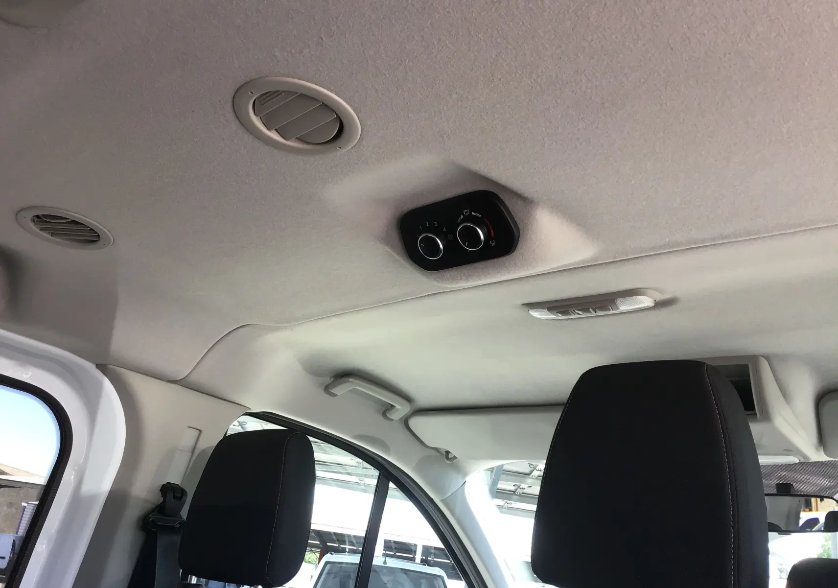 Vue intérieure du plafond et des aérateurs arrière du Ford Transit Custom Kombi blanc, avec commandes de ventilation au plafond.