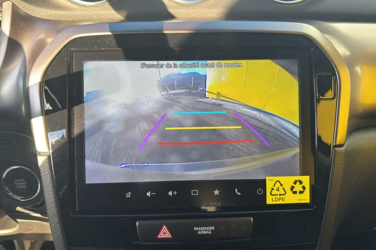 Écran multimédia 9 pouces affichant la caméra de recul du Suzuki Vitara 2025, intérieur noir avec bouton start/stop visible.