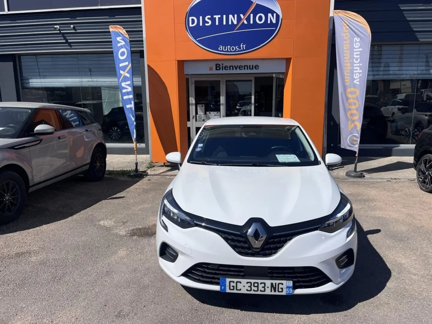 Renault Clio 1.6 E-Tech blanc Quartz vue de face, stationnée devant une concession Distinxion.