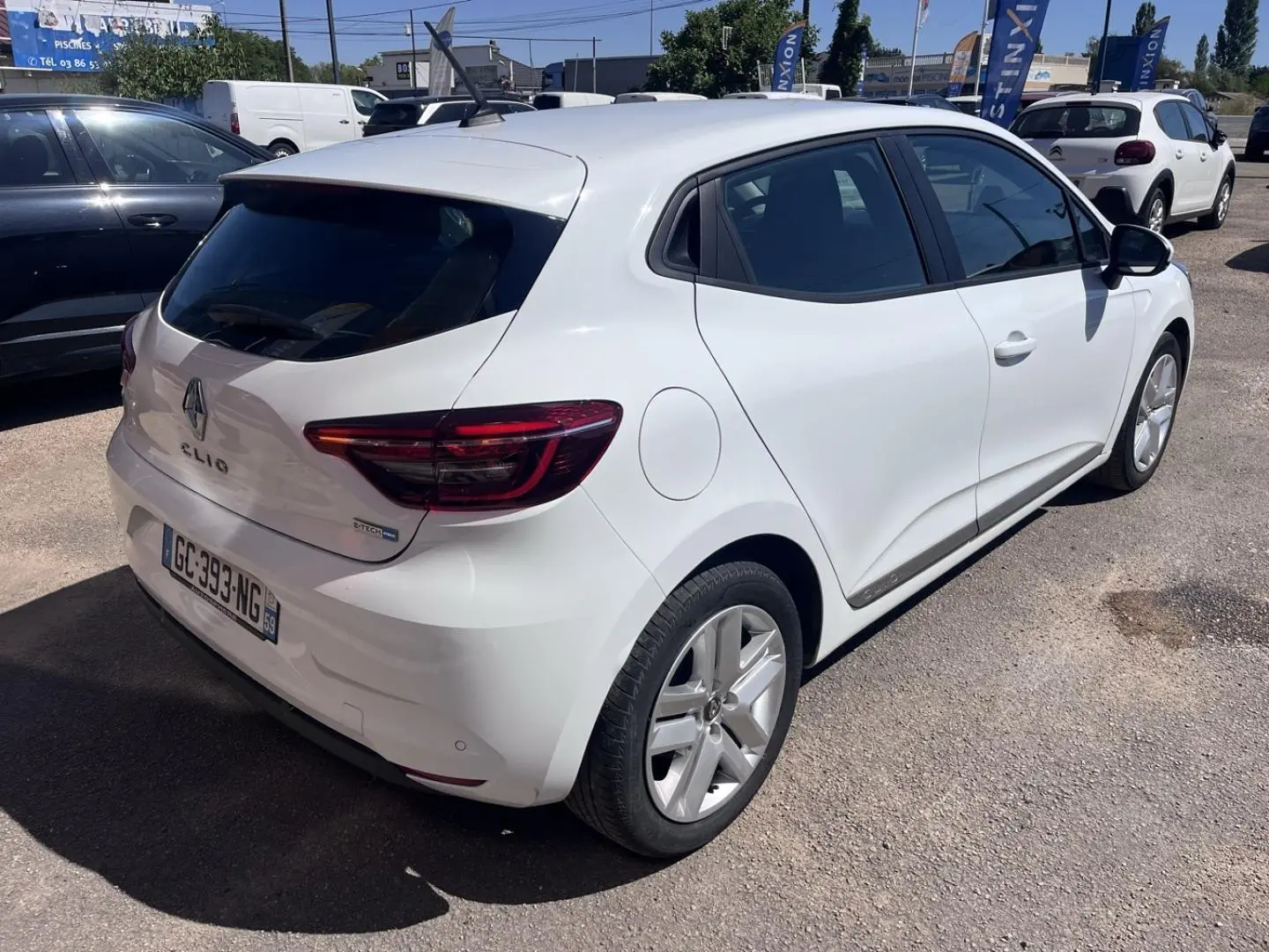Renault Clio blanc quartz vue 3/4 arrière droit avec becquet et feux arrière LED visibles.