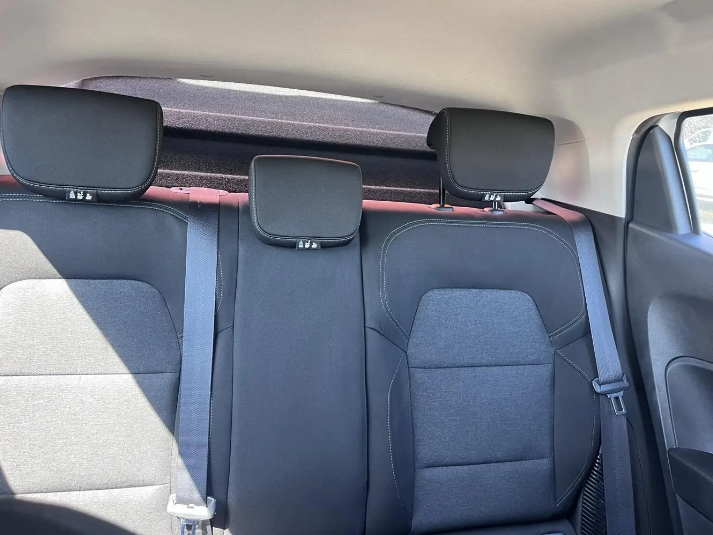 Vue intérieure arrière de la Renault Clio 1.6 E-Tech 2021, sièges tissu noir avec appuie-têtes et ceintures visibles.