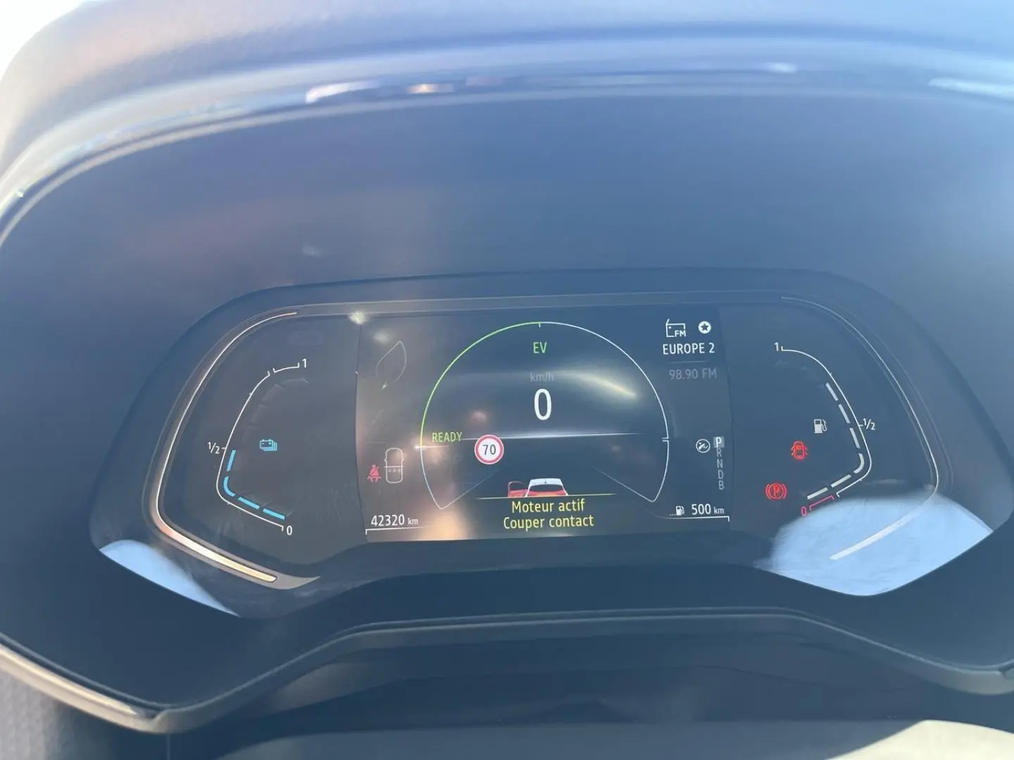 Tableau de bord numérique de Renault Clio 1.6 E-Tech blanc, affichant vitesse zéro et alertes moteur actives.