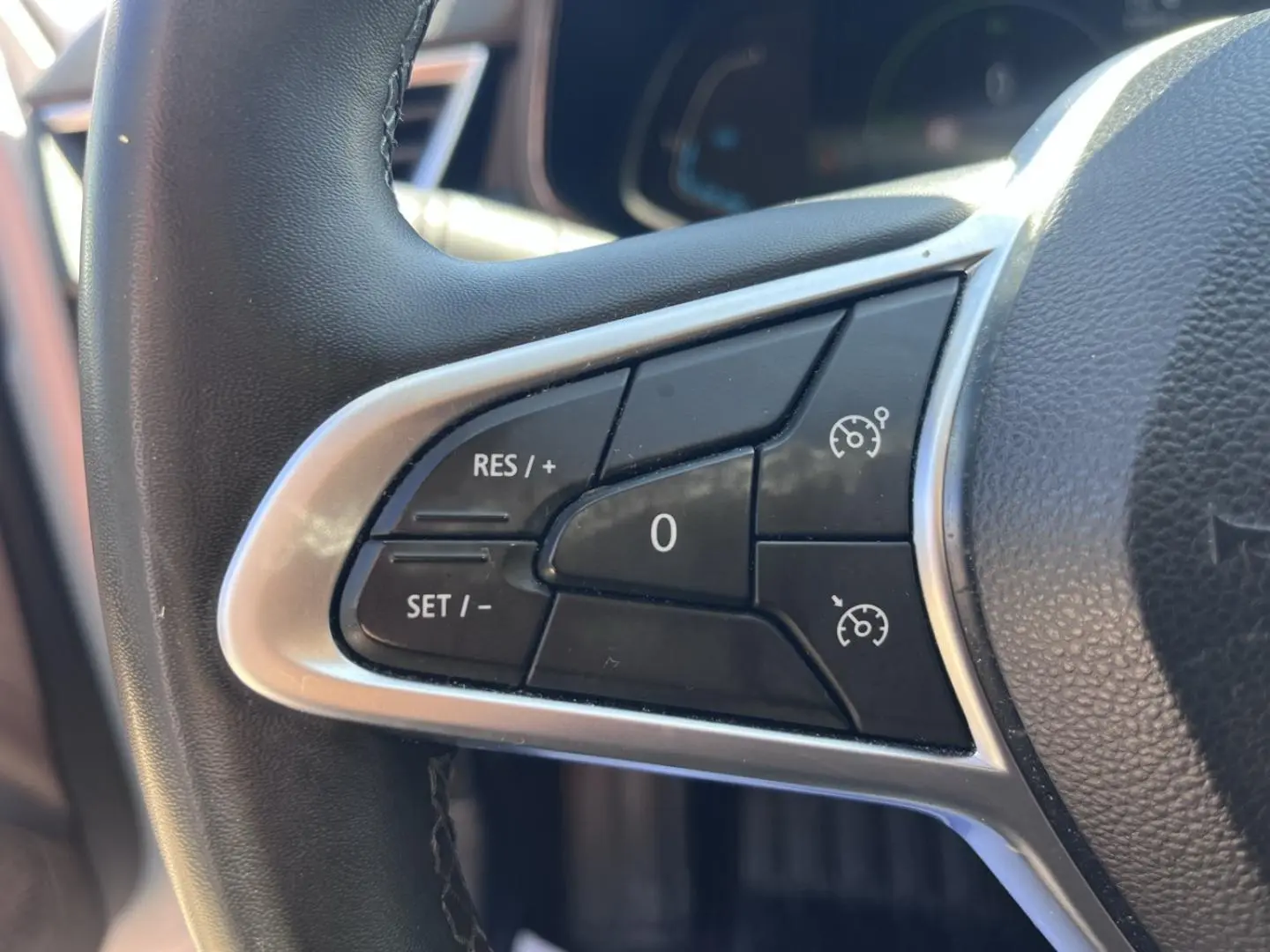 Gros plan sur les commandes de régulateur de vitesse au volant noir de la Renault Clio Blanc Quartz 2021.