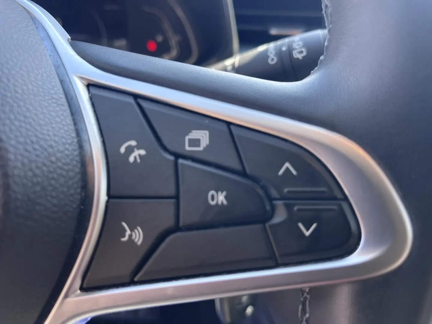 Gros plan sur les commandes multifonctions noires du volant de la Renault Clio 1.6 E-Tech blanc Quartz, version 2021.