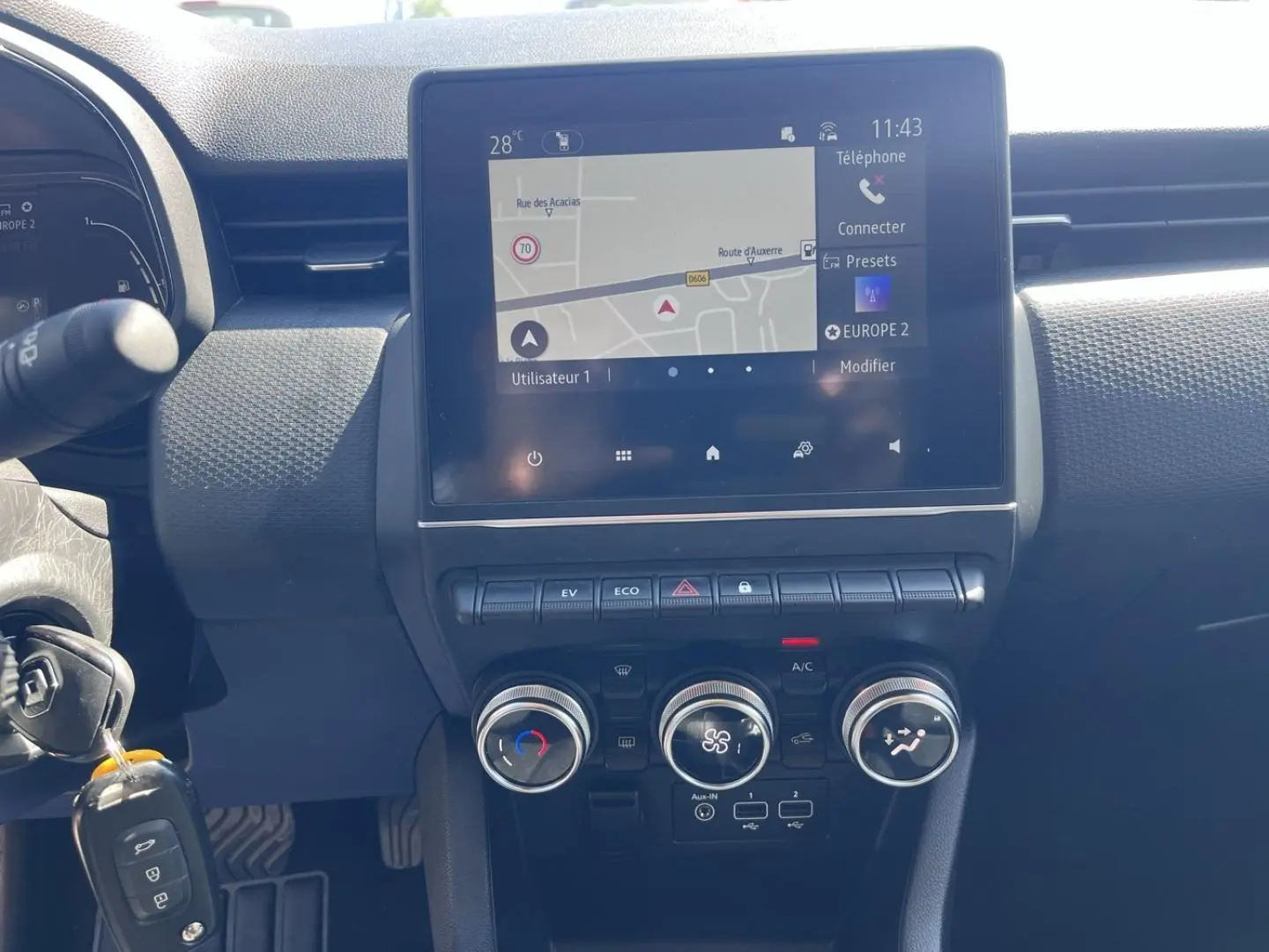 Tableau de bord de Renault Clio 1.6 E-Tech 2021 avec écran tactile GPS et commandes climatisation manuelle en vue frontale.