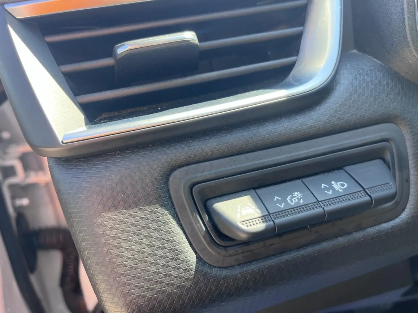 Gros plan sur les commandes de réglage des aides à la conduite et éclairage dans l’habitacle de la Renault Clio blanc Quartz.