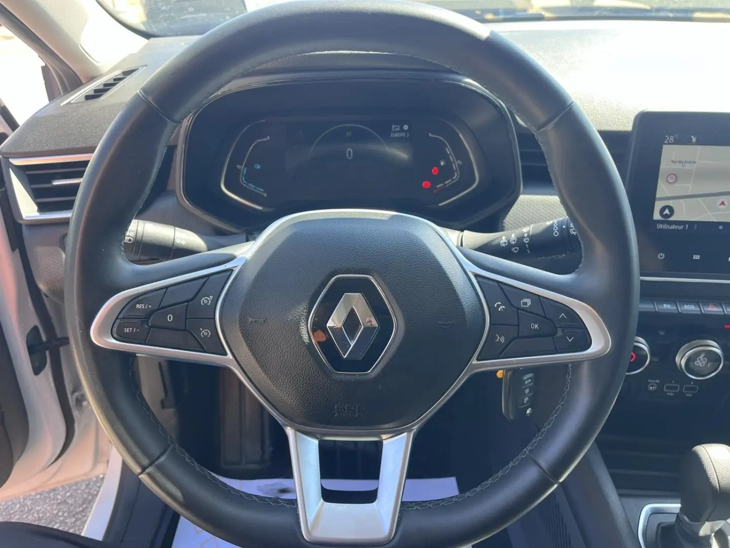 Vue centrée sur le volant noir de la Renault Clio 1.6 E-Tech 2021 avec tableau de bord digital et écran tactile latéral.