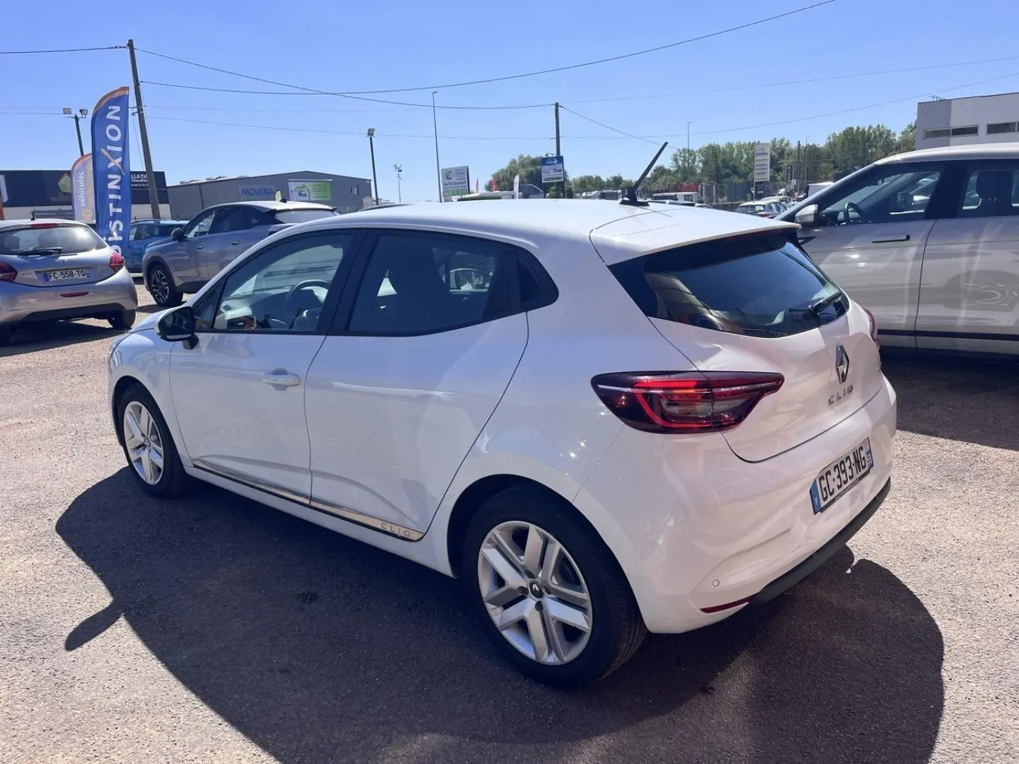 Renault Clio blanc Quartz vue 3/4 arrière droit, avec feux LED et jantes alliage visibles.