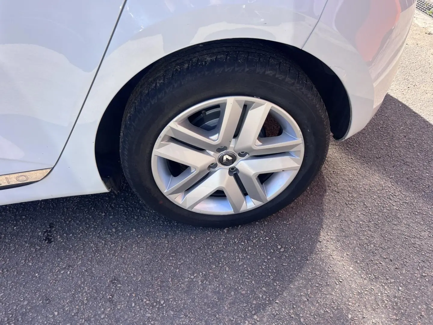 Gros plan sur la roue arrière droite d'une Renault Clio blanc Quartz avec jante alliage et partie de la carrosserie visible.